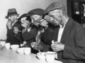 Великая депрессия в США: безработные мужчины обедают хлебом и супом, полученными в очереди за бесплатным питанием