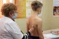 Врач-педиатр проводит аускультацию лёгких у подростка